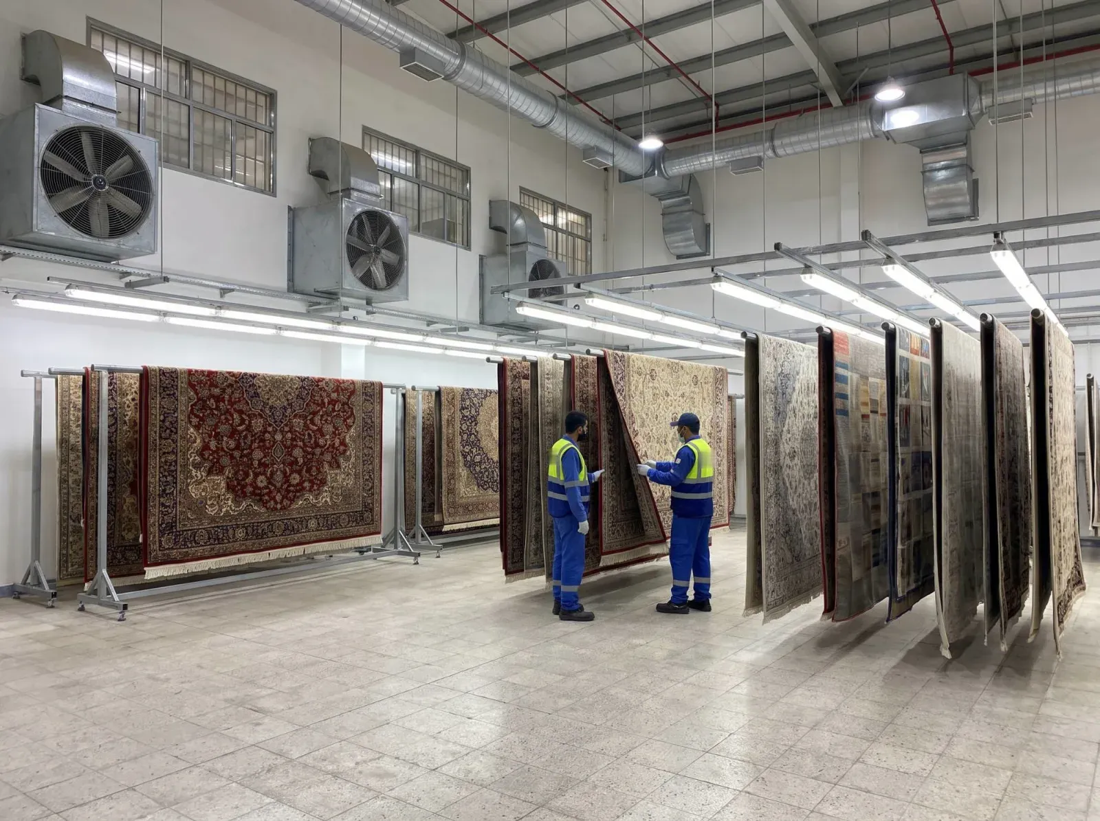Чистые ковры сушатся на стойках в сушильном помещении цеха